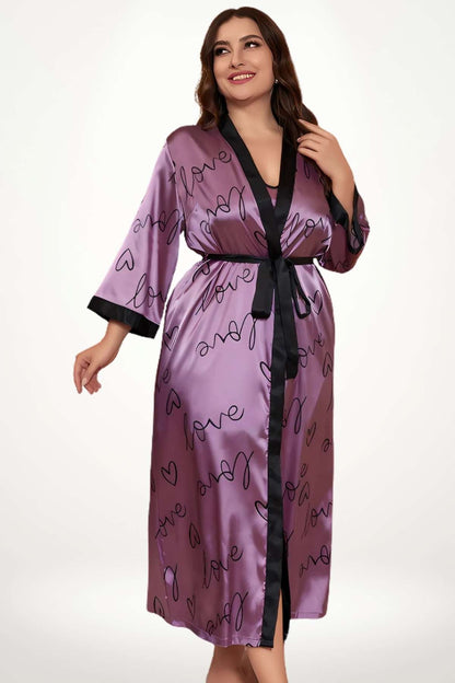 Kimono satin violet avec motifs de cœurs noirs, porté par une femme souriante, fond neutre