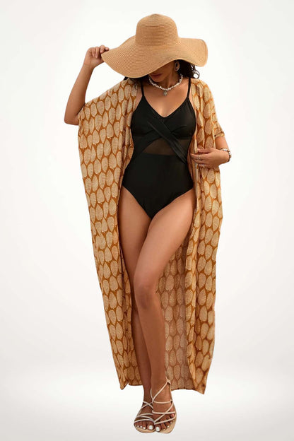 Femme en maillot noir portant un kimono à motifs dorés, chapeau large, posant sur fond clair