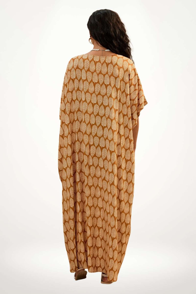 Femme portant un kimono beige à motifs de feuilles, dans une posture décontractée, sur fond clair
