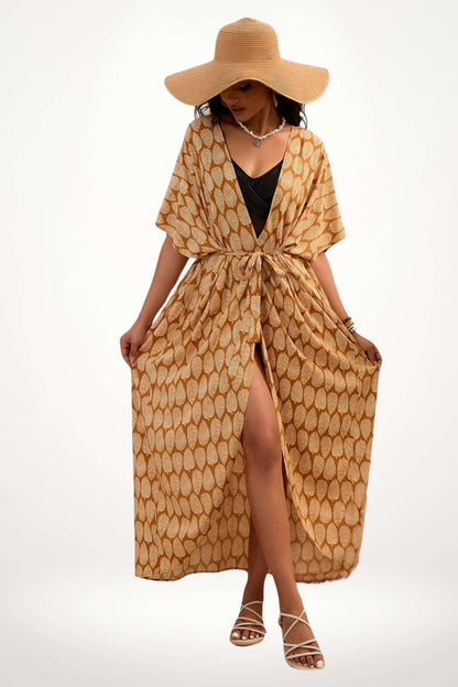 Femme en kimono beige à motifs feuilles, portant un grand chapeau, dans une posture élégante et décontractée