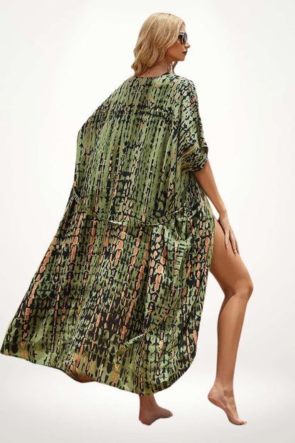 Femme en kimono vert à motifs, posant élégamment, pieds nus sur un fond neutre