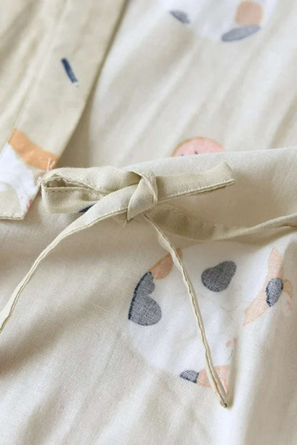 Détail d'un kimono en tissu doux avec motifs de cœurs colorés sur fond beige et ceinture nouée