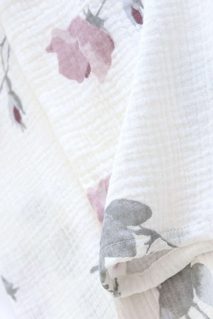 Tissu léger blanc avec motifs floraux roses et gris, offrant une texture douce et confortable