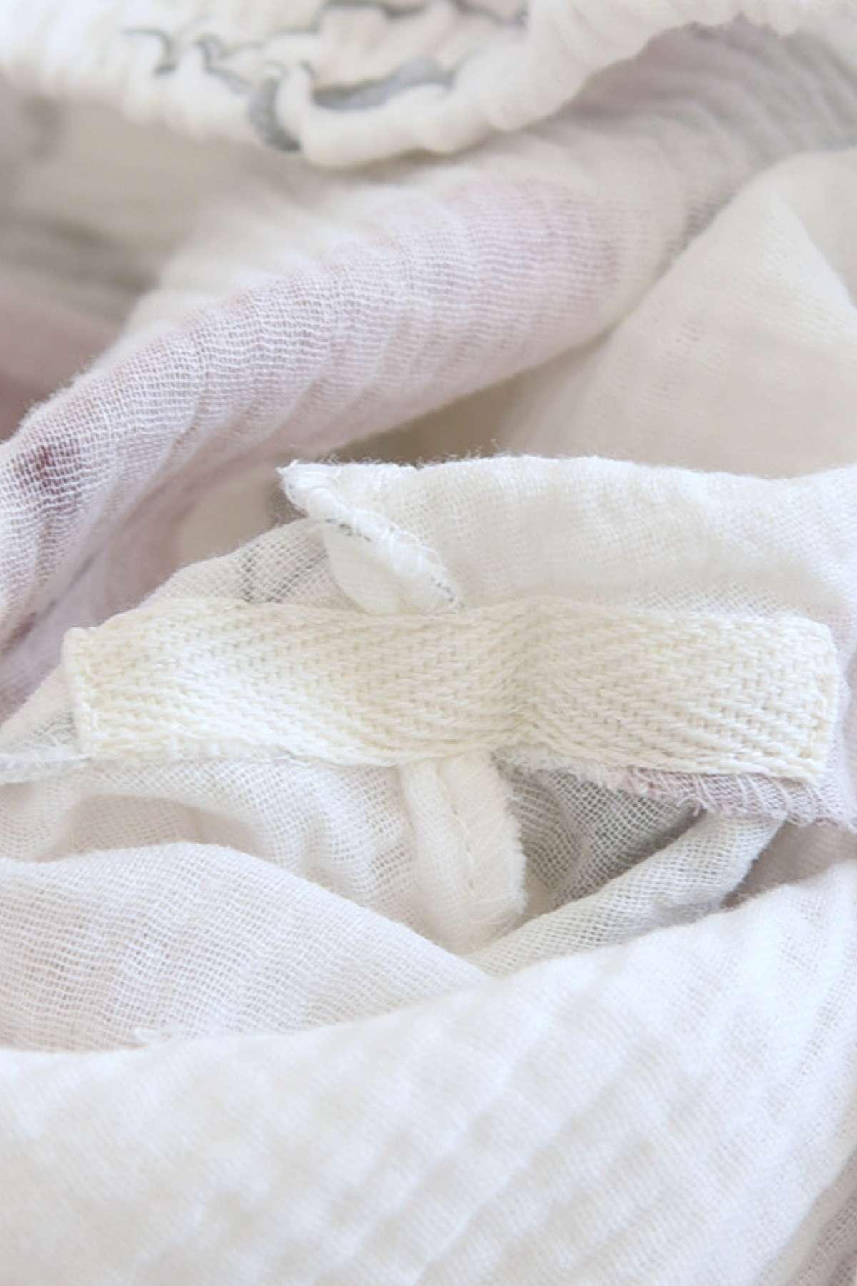 Tissu léger et doux en blanc, avec des motifs délicats, offrant une sensation de confort et de douceur
