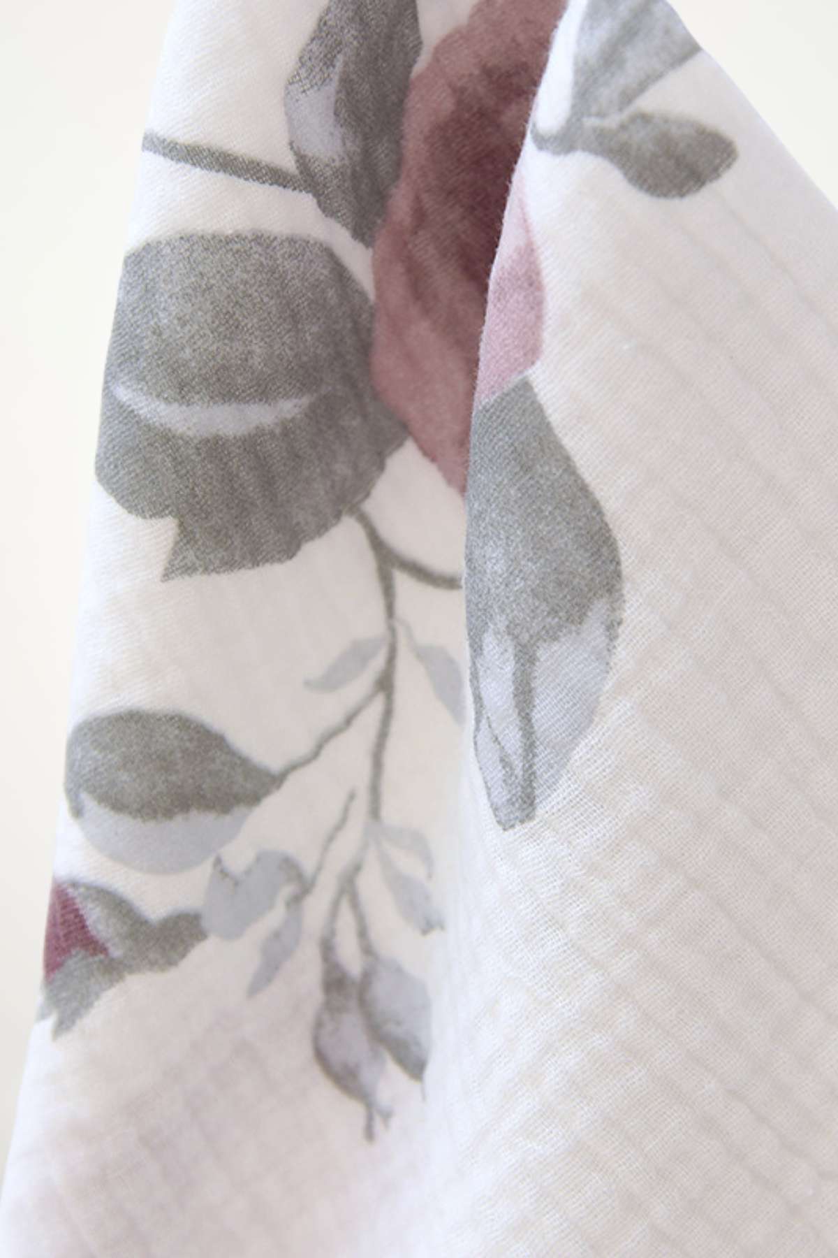 Tissu léger avec motifs floraux en gris et rose sur fond blanc, évoquant confort et douceur