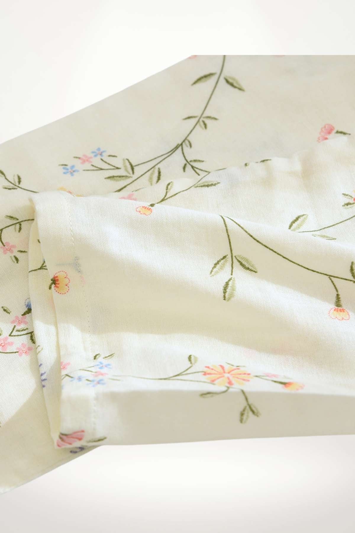 Tissu léger de couleur crème avec motifs floraux délicats en rose et bleu sur fond uni