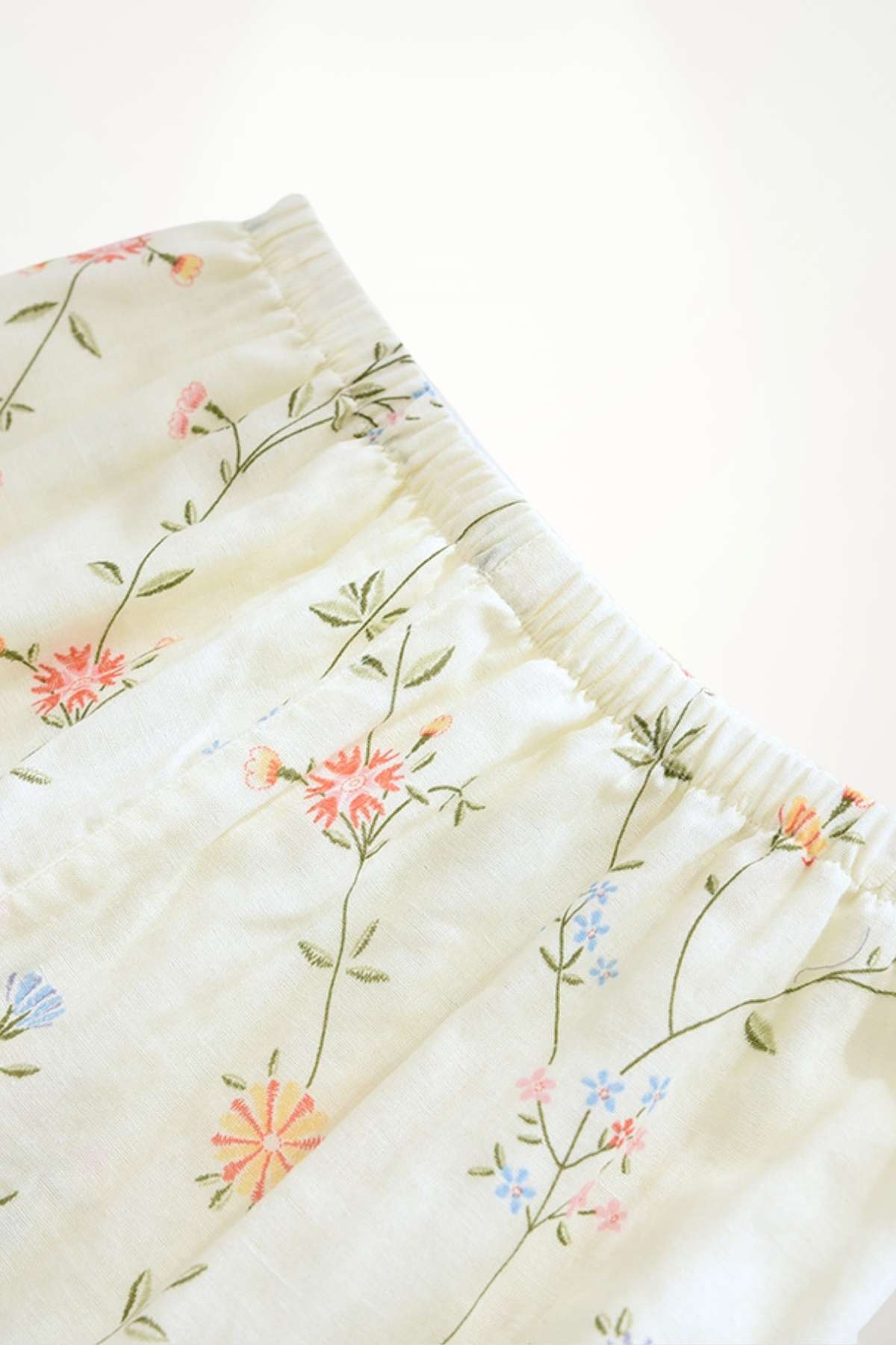 Pantalon léger en tissu doux avec motifs floraux colorés sur fond crème, idéal pour un style de pyjama confortable