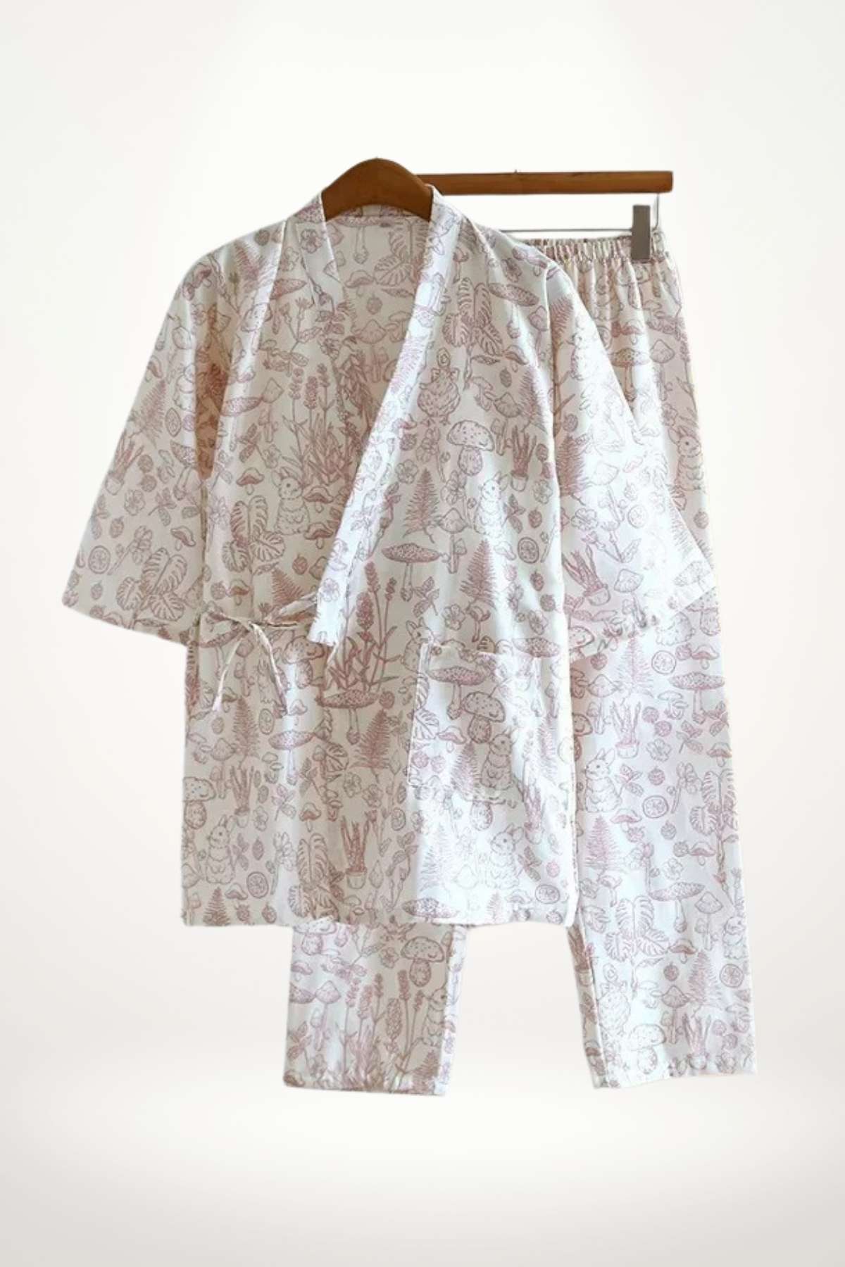 Un kimono en coton doux avec un motif floral rose clair, suspendu à un cintre en bois