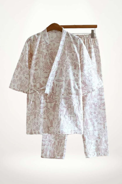 Un kimono en coton doux avec un motif floral rose clair, suspendu à un cintre en bois