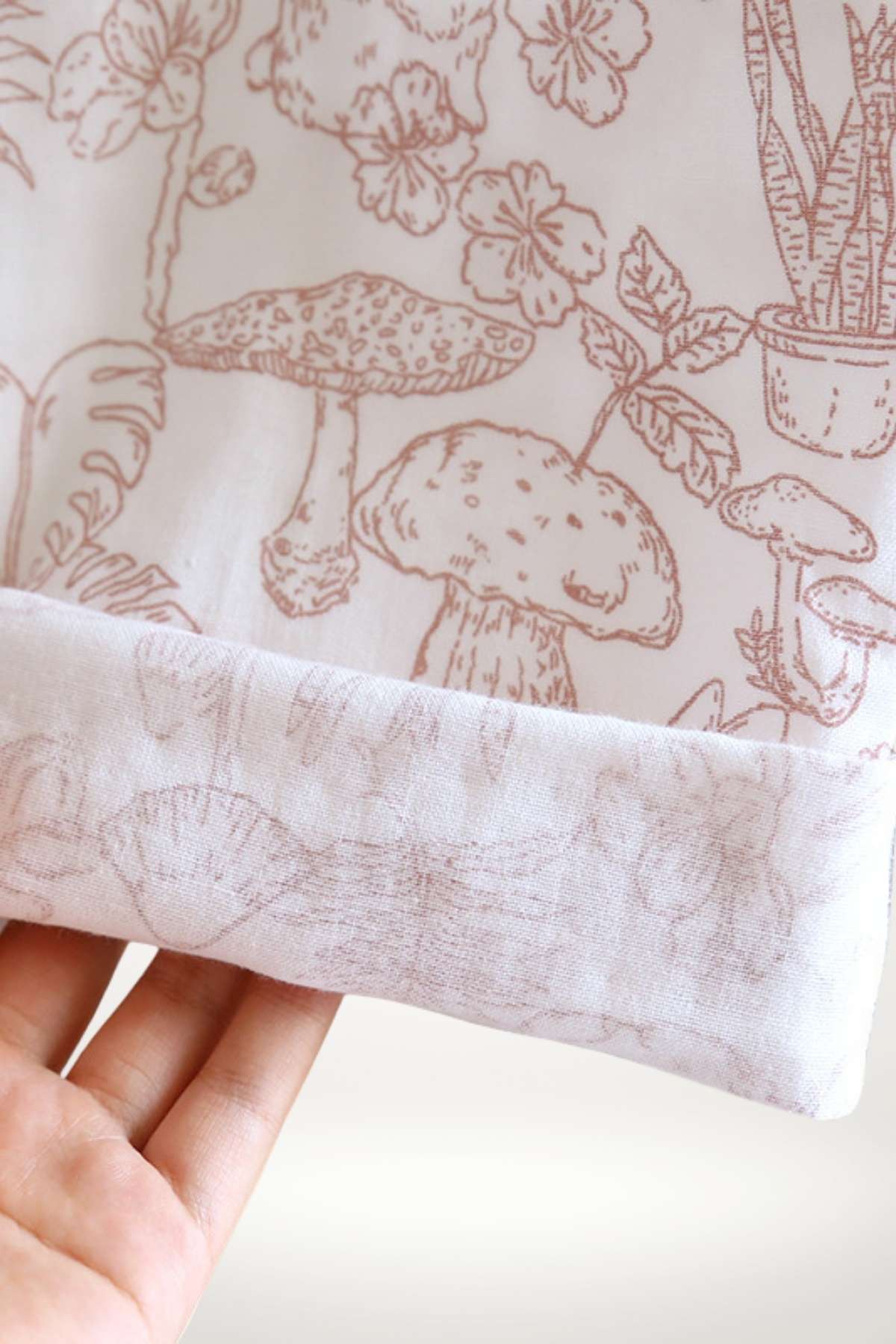 Tissu en coton doux avec motifs floraux et champignons dans des tons rose pâle sur fond blanc