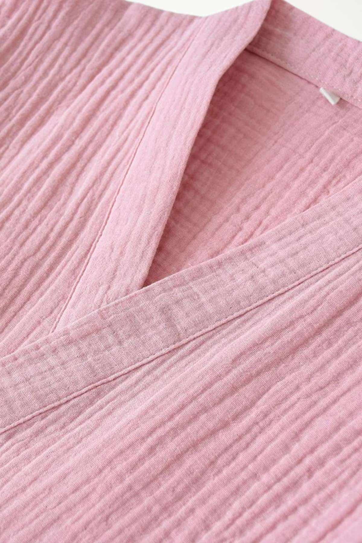 Kimono en tissu rose texturé, avec un col en V et des plis délicats, idéal pour une tenue de nuit