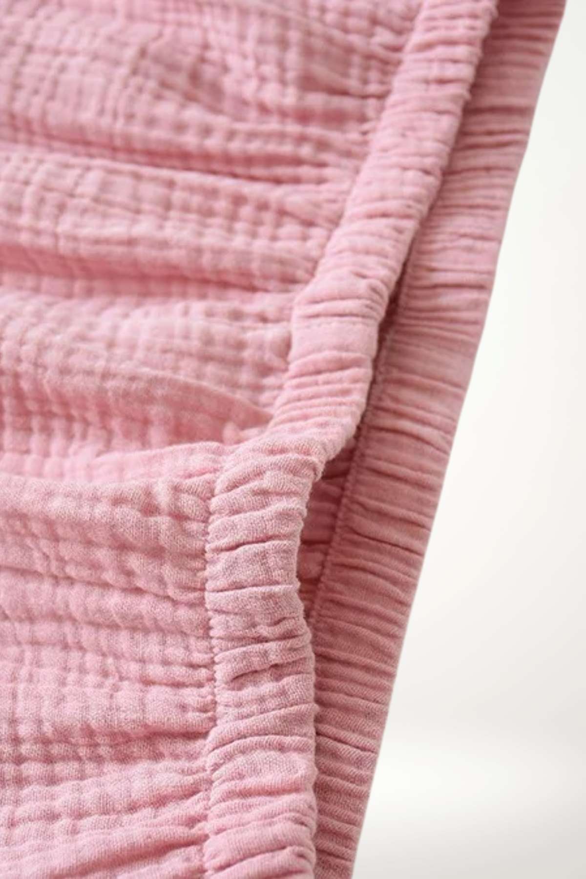 Tissu rose texturé, doux et froissé, avec des plis marqués, évoquant un kimono confortable pour la nuit