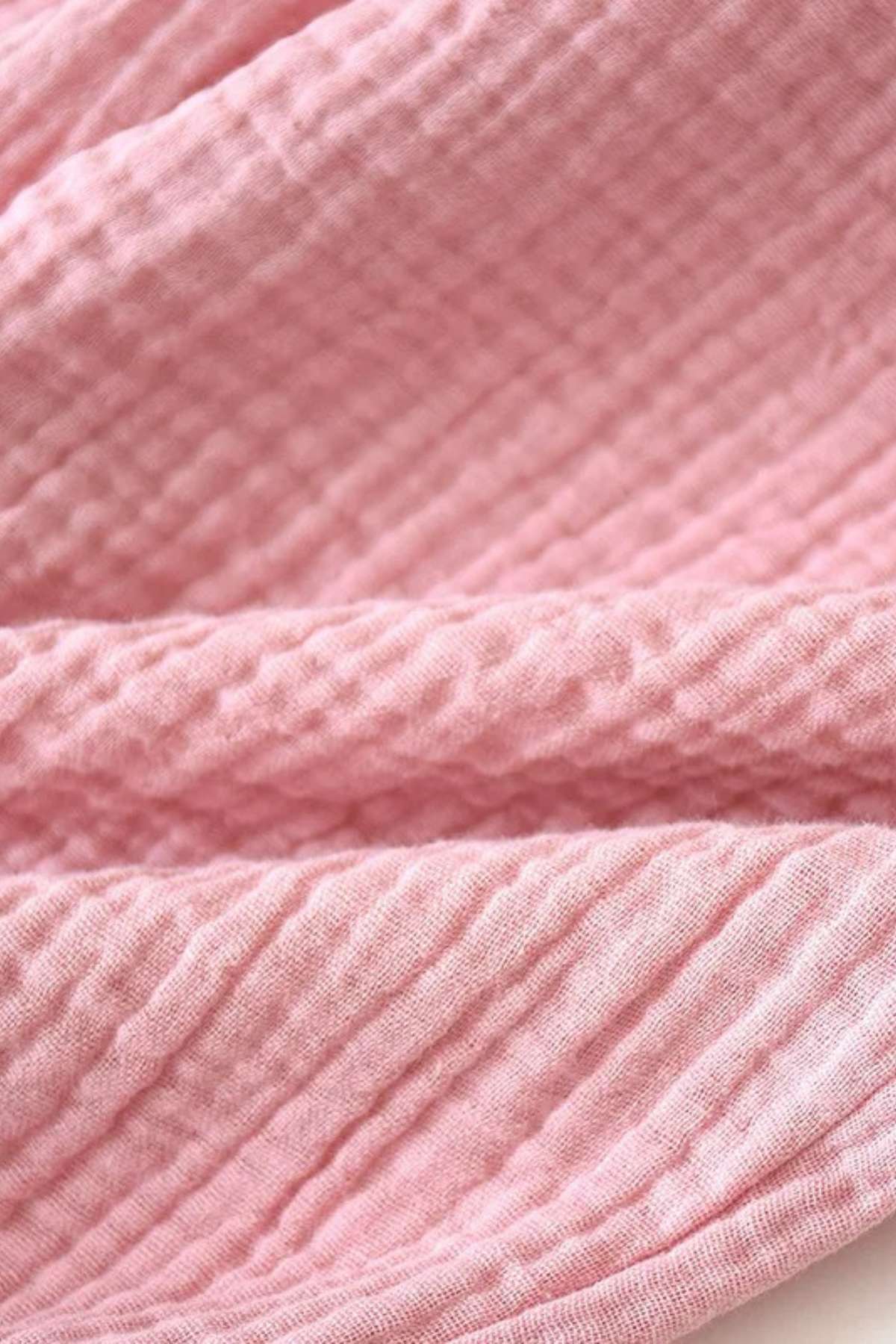 Tissu en coton rose avec une texture gaufrée, plié de manière douce et élégante