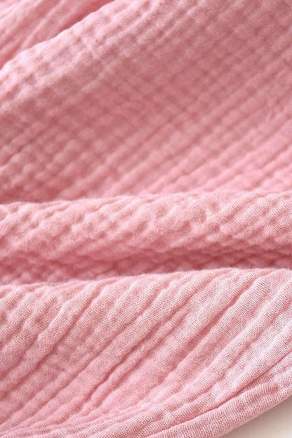Tissu en coton rose avec une texture gaufrée, plié de manière douce et élégante