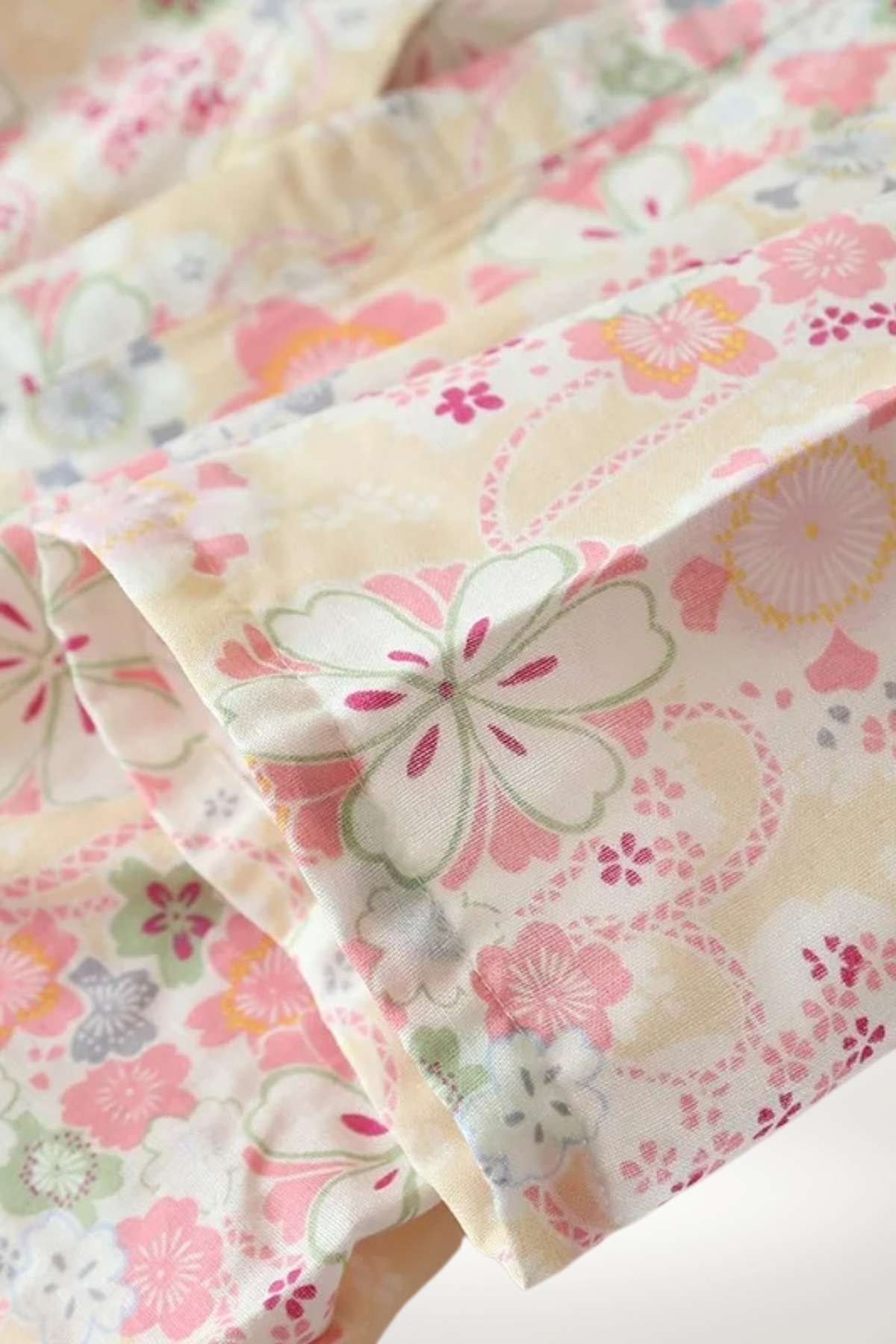 Tissu de kimono avec motifs floraux colorés, dominé par des teintes pastel de rose et vert