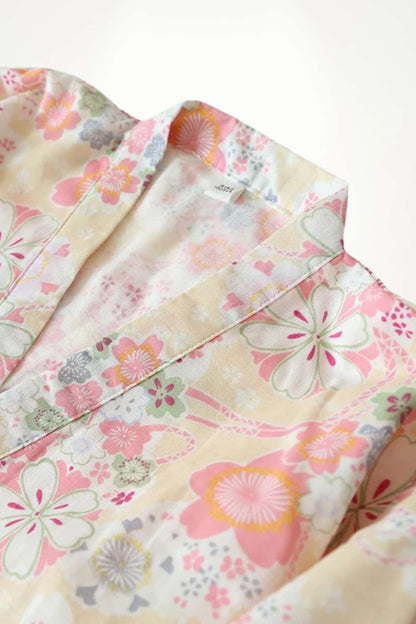Kimono féminin en tissu léger avec motifs floraux colorés sur fond crème, dégageant une ambiance douce et élégante