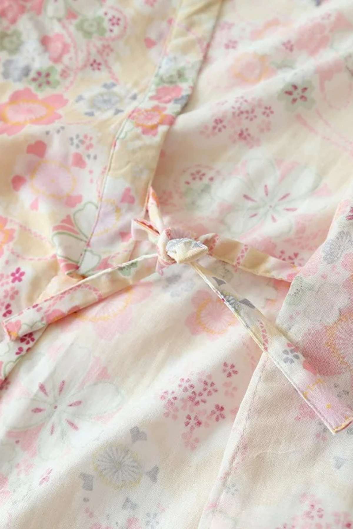 Tissu léger de kimono avec motifs floraux pastel sur fond crème, noué délicatement sur le côté