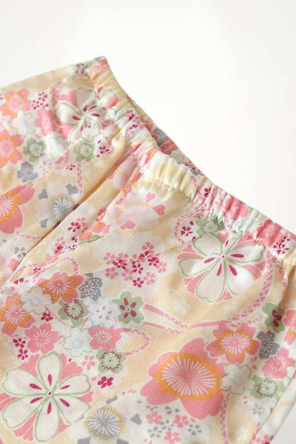 Pantalon en tissu léger aux motifs floraux colorés, dominé par des teintes de rose, jaune et vert