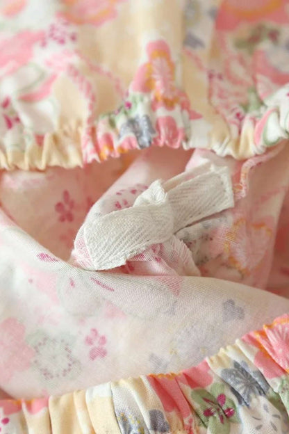 Tissu léger aux motifs floraux roses et jaunes, avec des fronces et un lien en tissu blanc