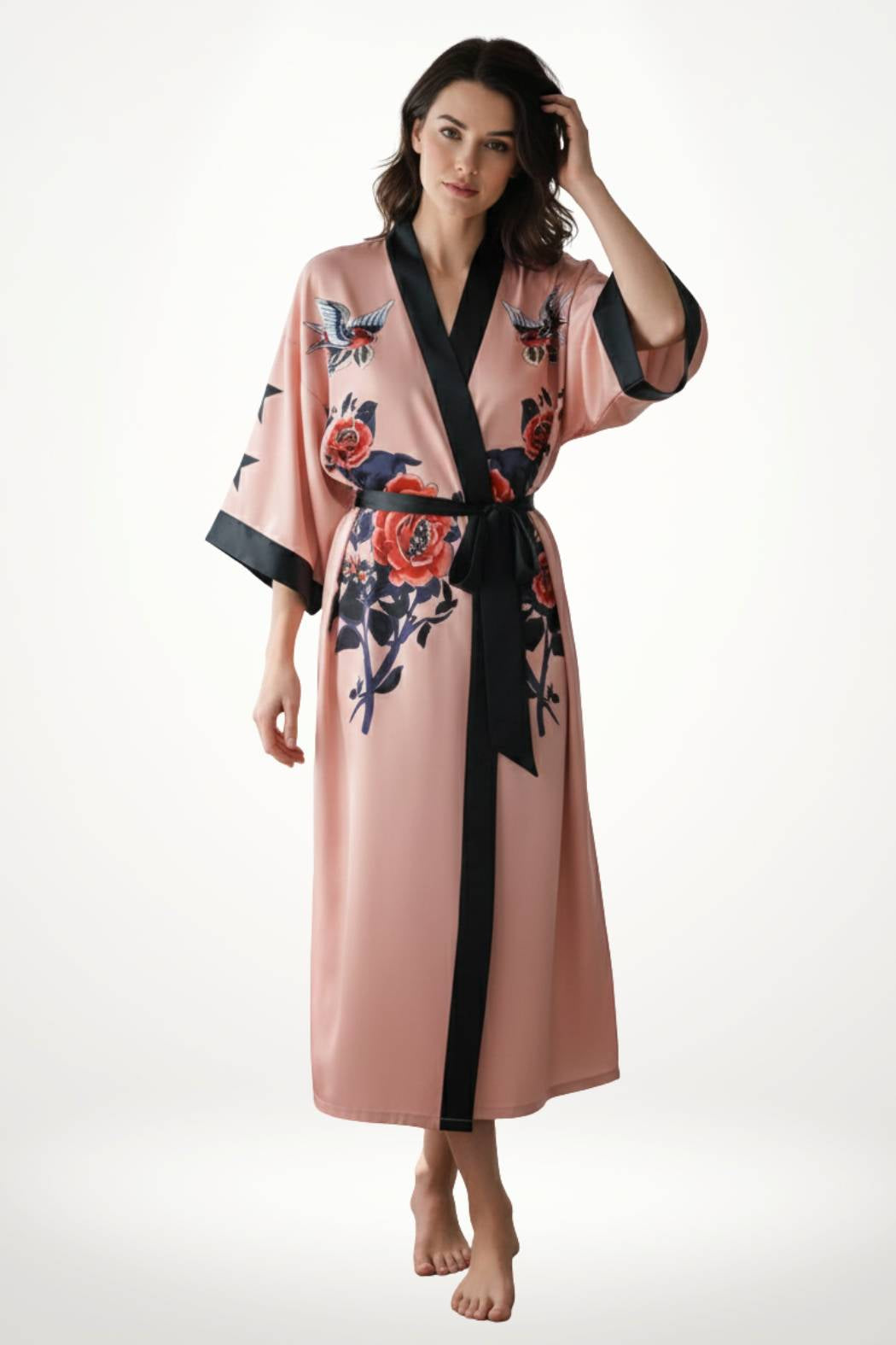 Kimono long en satin rose avec motifs floraux, ceinture noire, porté par une femme debout sur un fond blanc