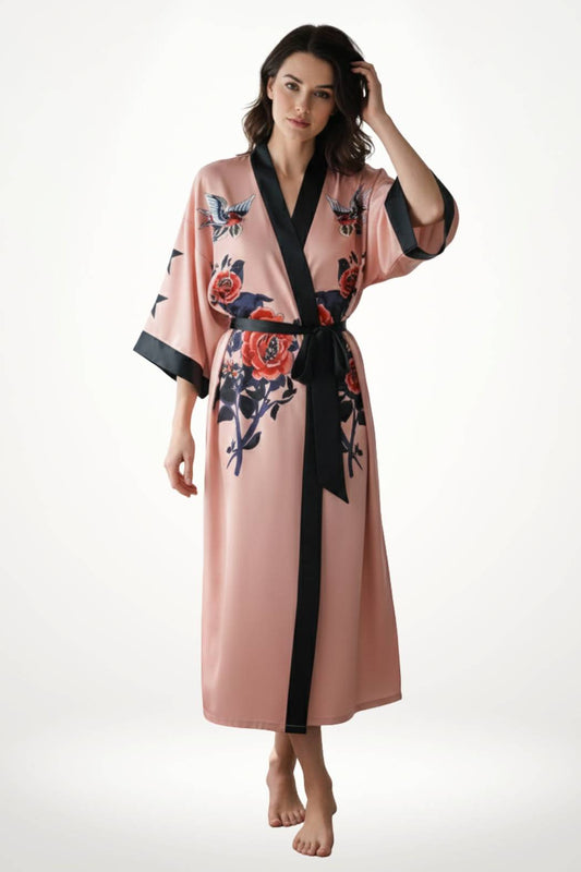 Kimono long en satin rose avec motifs floraux, ceinture noire, porté par une femme debout sur un fond blanc