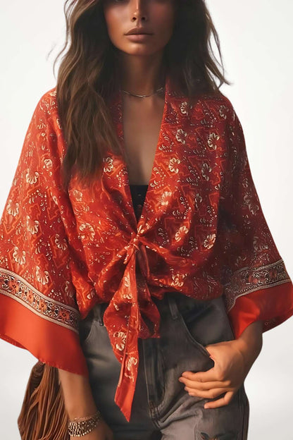 Femme portant un kimono rouge à motifs floraux, avec des manches larges et un décor minimaliste en arrière-plan