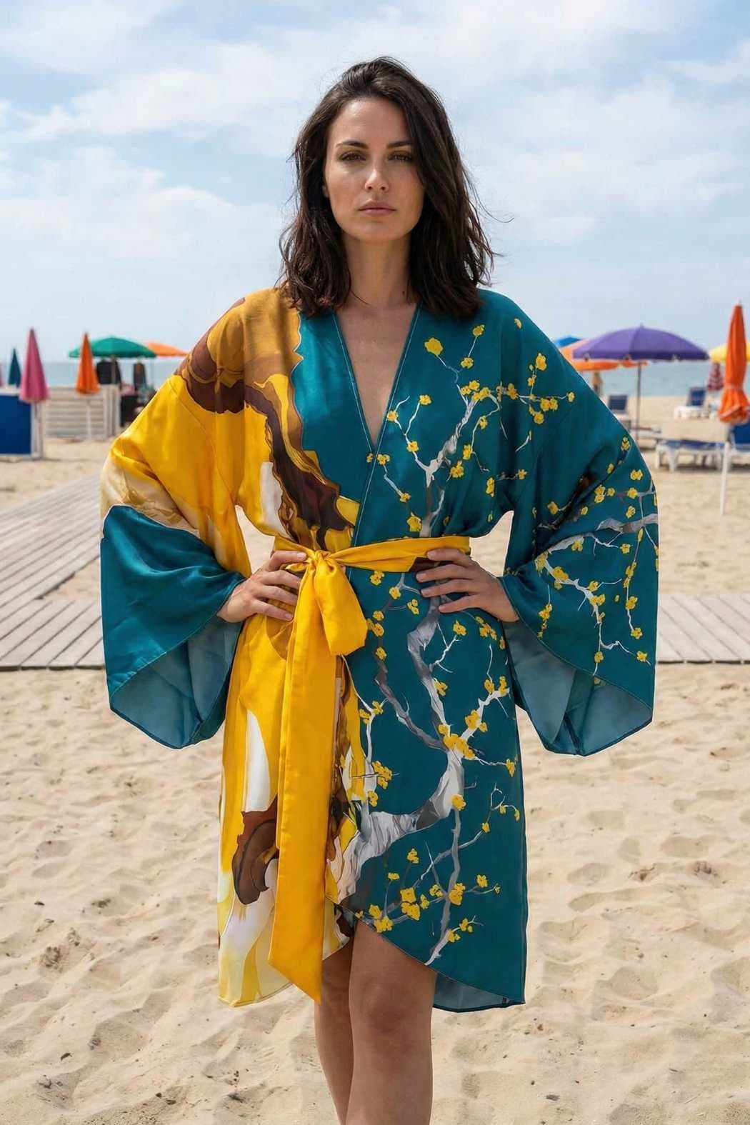 Femme portant un kimono en satin bleu et jaune, décoré de motifs floraux, sur une plage ensoleillée