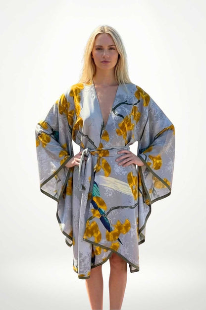 Robe kimono chic grise ornée de motifs floraux jaunes, portée par une femme aux cheveux blonds, dans un décor minimaliste
