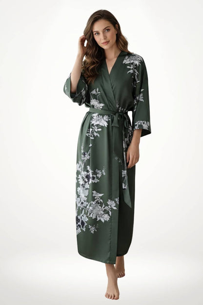 Femme portant un kimono vert foncé avec des motifs floraux blancs, debout sur un sol clair et nu