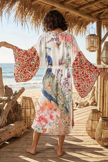 Kimono en satin aux motifs floraux et d'oiseaux, porté par une femme dans un décor de plage en bois