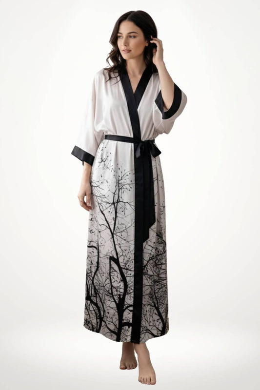 Kimono long en satin blanc avec motifs d'arbres noirs, ceinturé, porté par une femme aux cheveux ondulés