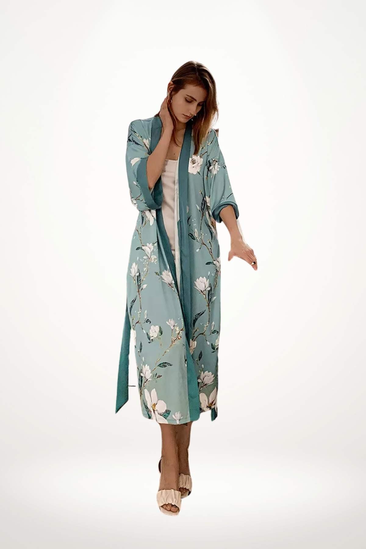 Femme portant un kimono léger turquoise avec des motifs floraux, dans une posture élégante sur fond blanc