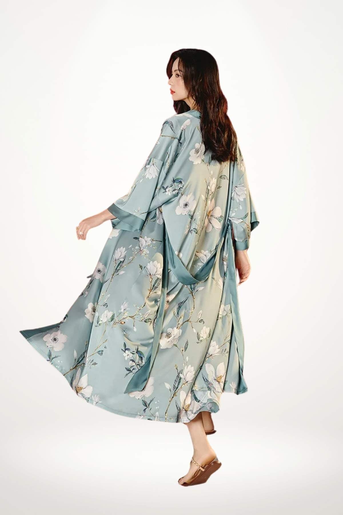 Femme en kimono léger bleu avec motifs floraux, se retournant, sur fond blanc lumineux