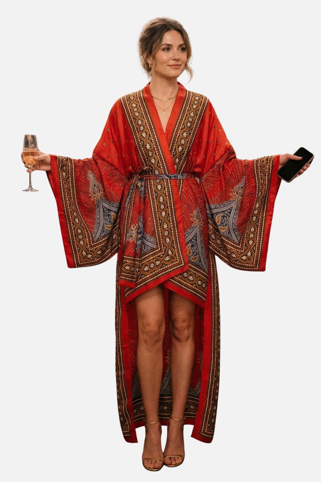 Femme portant un kimono rouge en soie avec motifs tribaux, tenant un verre et un téléphone, dans un décor élégant