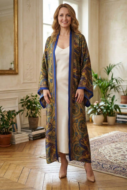 Femme souriante portant un kimono long aux motifs colorés, dans un intérieur lumineux avec des plantes