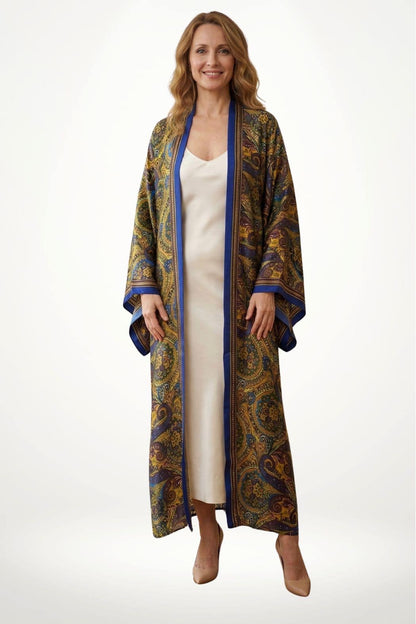 Femme souriante portant un kimono long aux motifs colorés, avec un fond blanc et des chaussures beiges