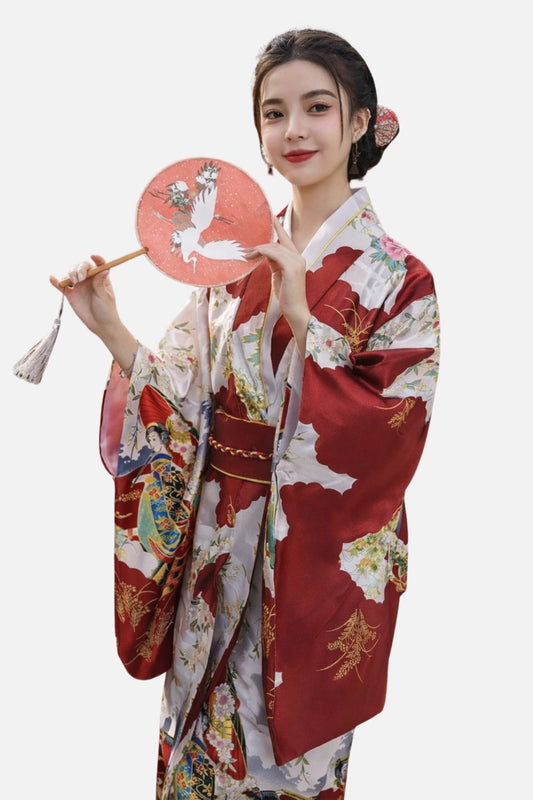 Femme en kimono aux motifs floraux, tenant un éventail rose, sur fond blanc, avec un élégant chignon