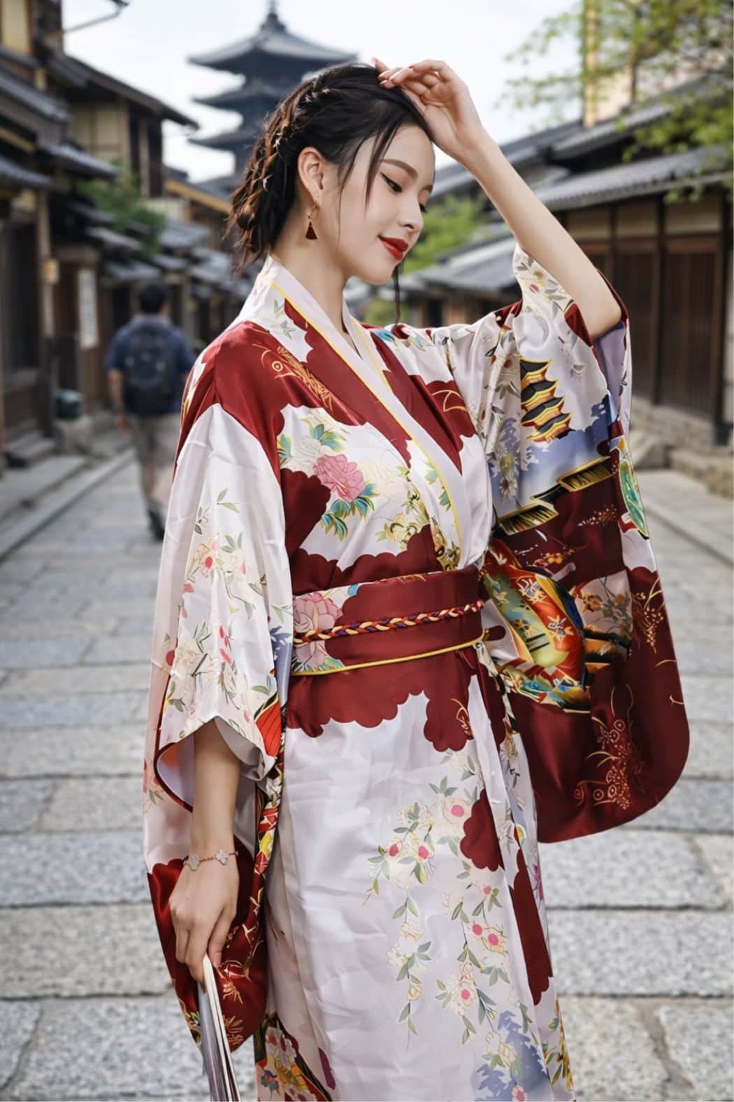 Femme en kimono rouge et blanc, décoré de fleurs, posant dans une rue traditionnelle avec des bâtiments en bois