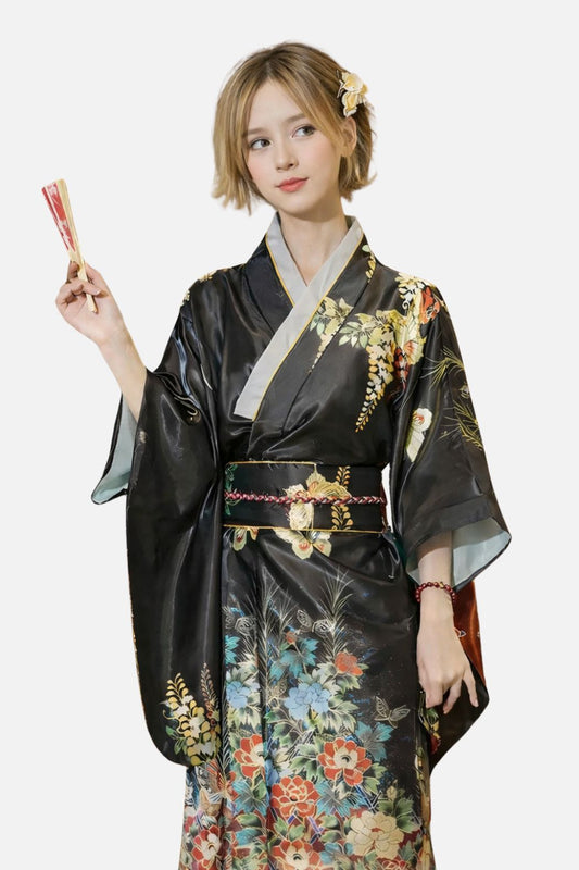 Femme en kimono noir brillant orné de fleurs colorées, tenant un éventail dans un décor minimaliste