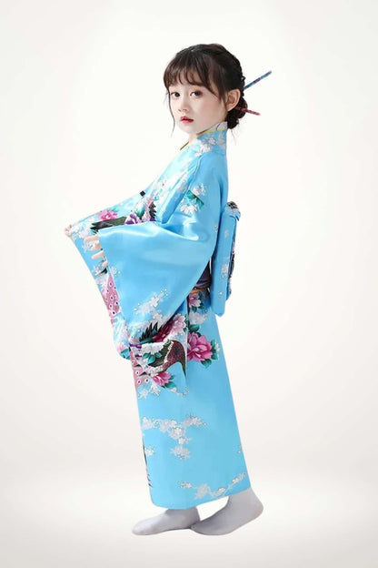 Une jeune fille porte un kimono bleu orné de fleurs et de motifs colorés, se tenant élégamment sur un fond