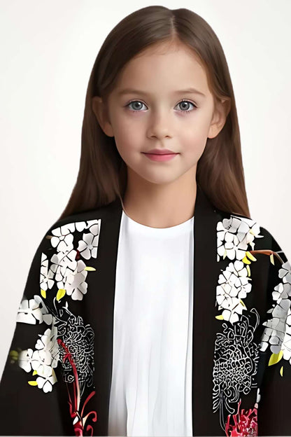 Une jeune fille porte un kimono noir fleuri, avec des motifs blancs et rouges, sur un fond clair