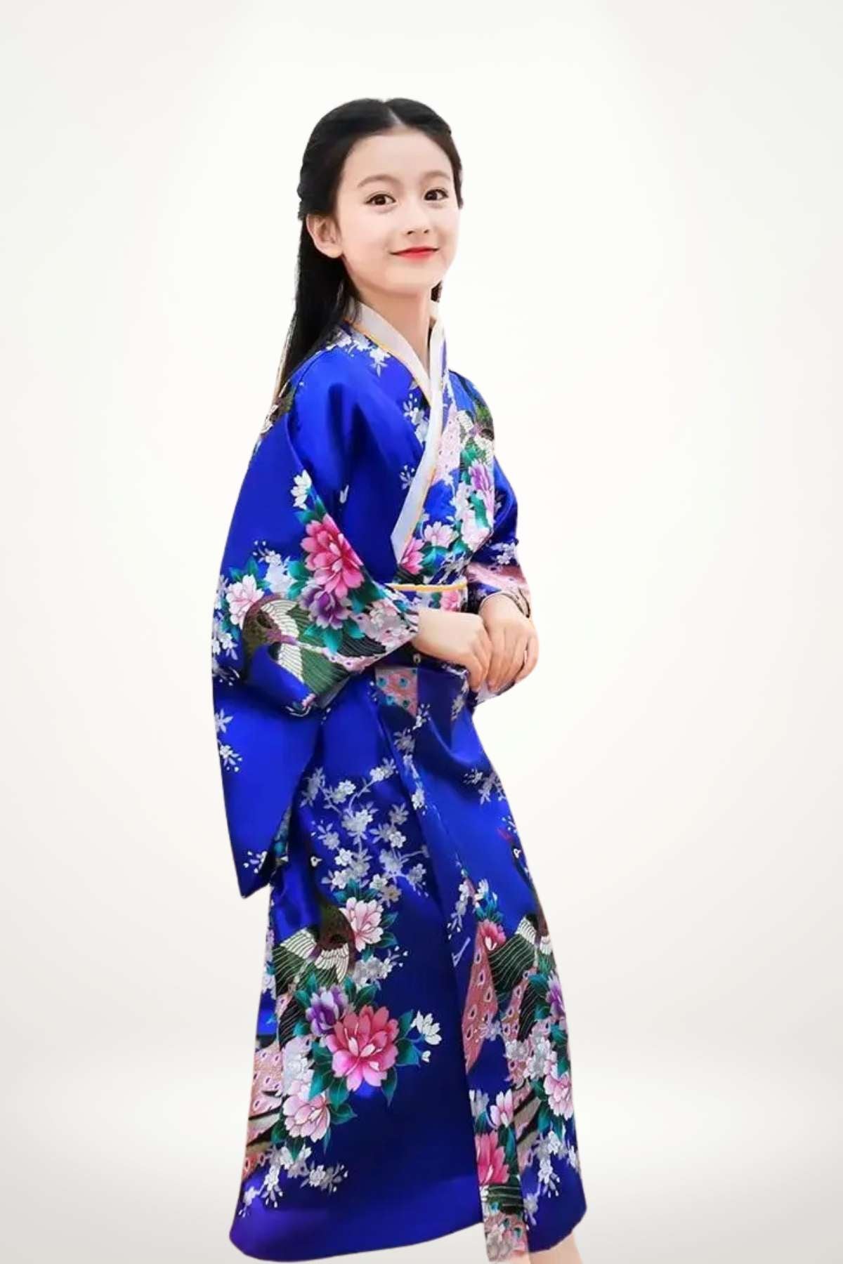 Fille souriante en kimono bleu vif orné de fleurs roses et blanches, posant sur fond neutre