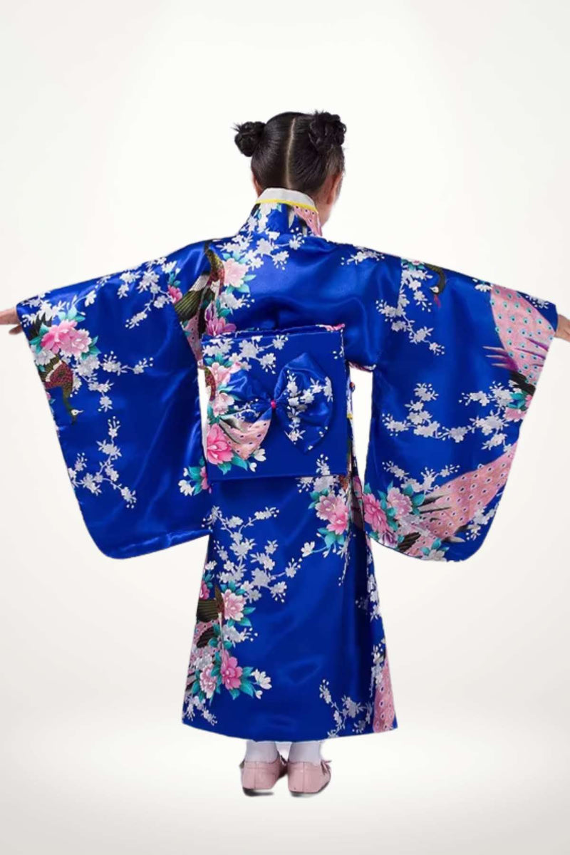 Une fille porte un kimono bleu vif orné de fleurs roses et de motifs traditionnels, avec des manches larges