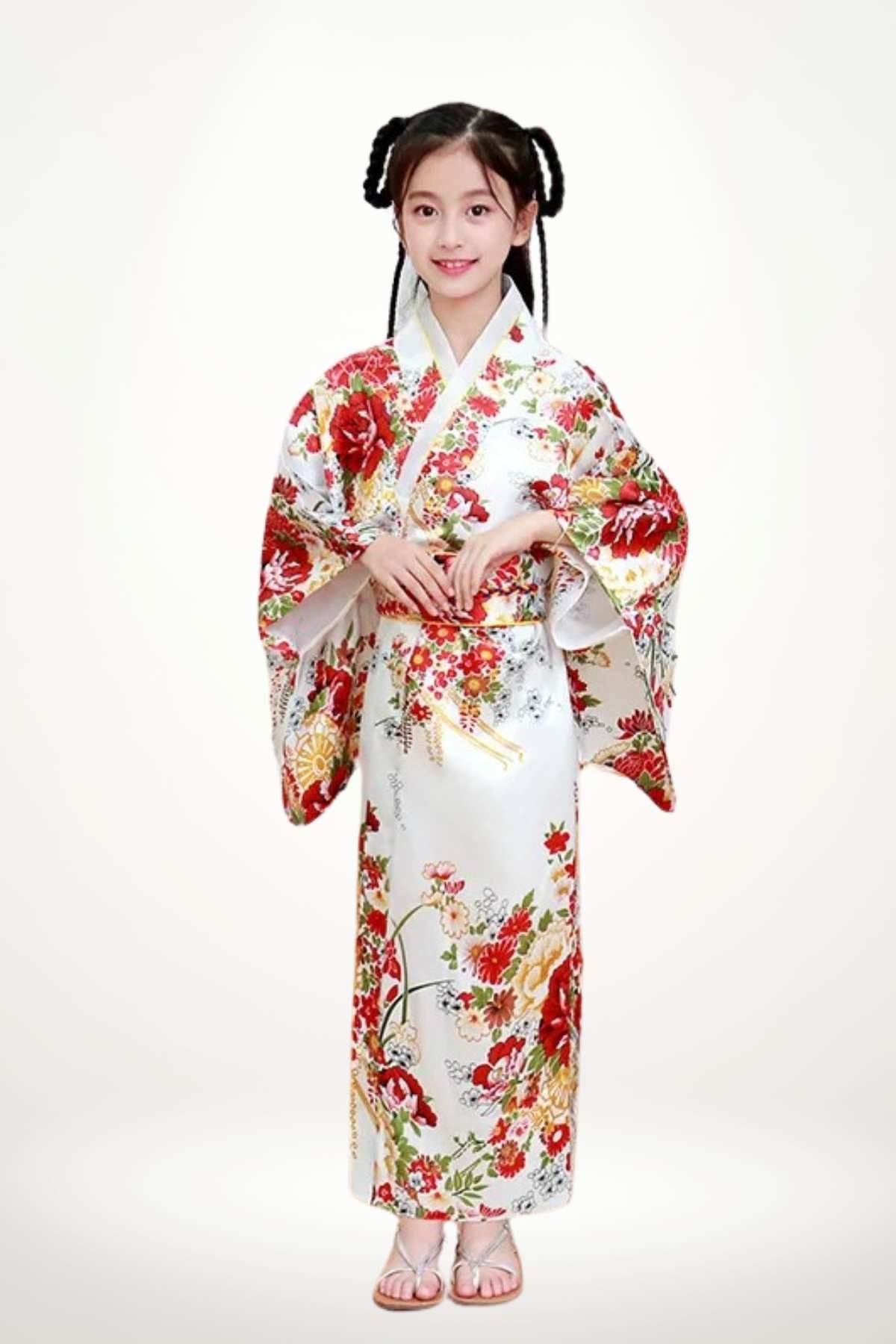 Fillette souriante portant un kimono blanc orné de fleurs rouges et jaunes, avec des manches larges et des sandales