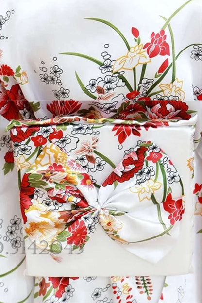 Kimono blanc orné de fleurs rouges et jaunes, avec un nœud décoratif et un fond floral coloré