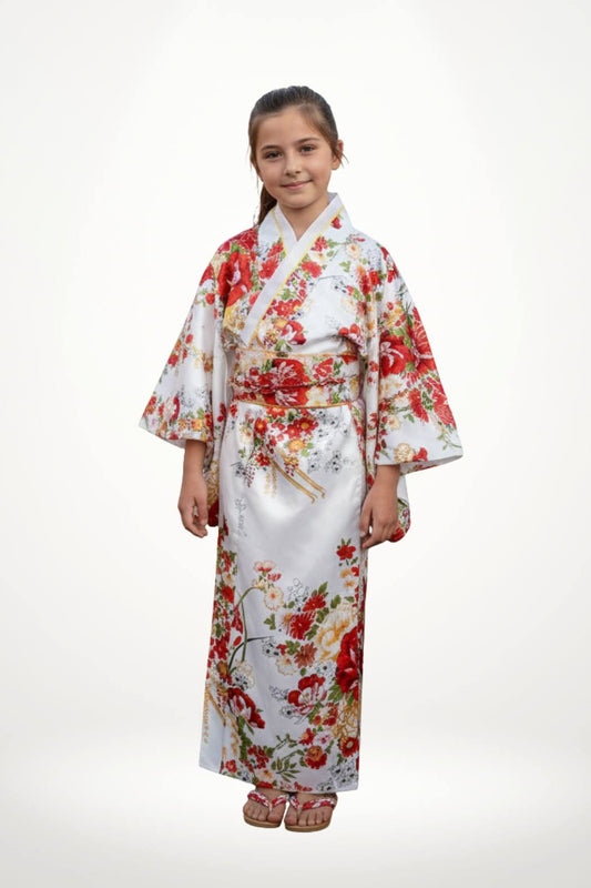 Fillette souriante portant un kimono blanc orné de fleurs rouges et jaunes, avec des manches larges et des sandales