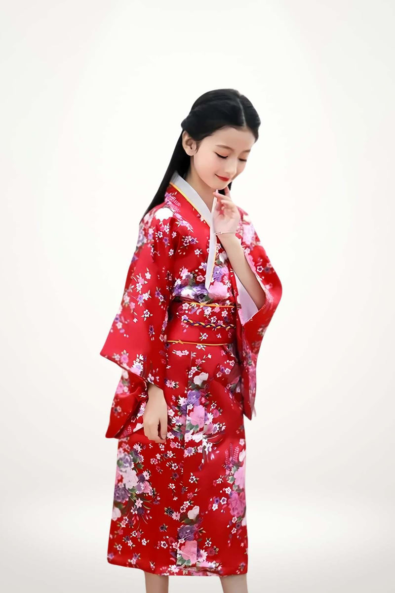 Fillette en kimono rouge à fleurs, posture délicate avec un léger sourire, fond neutre et lumineux