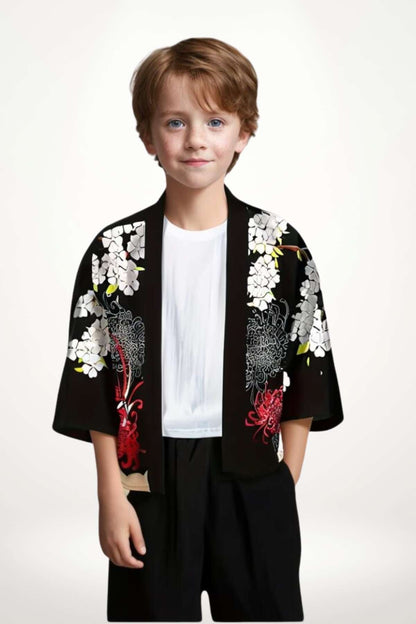 Un garçon porte un kimono noir orné de fleurs blanches et de motifs rouges, avec un fond neutre