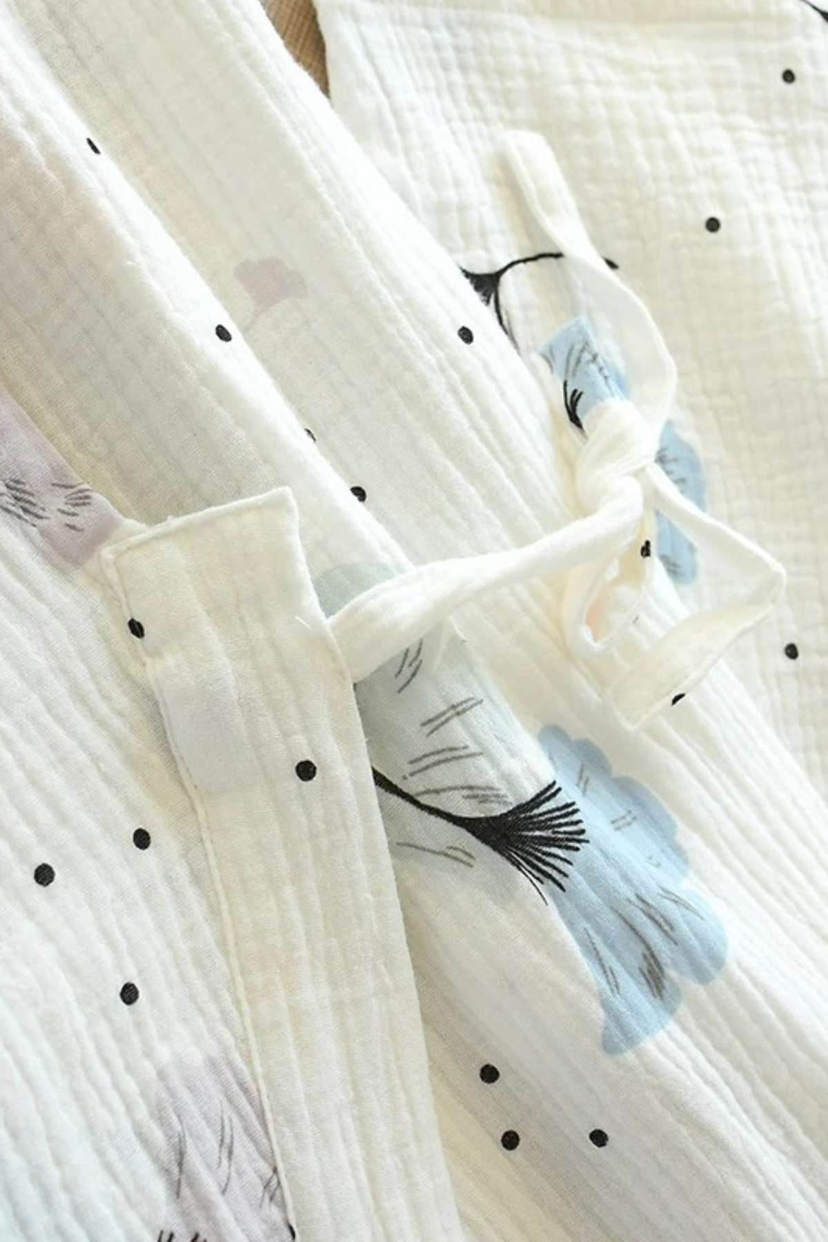 Kimono en gaze de coton blanc avec motifs floraux bleus et noirs, présentant une texture douce et légère