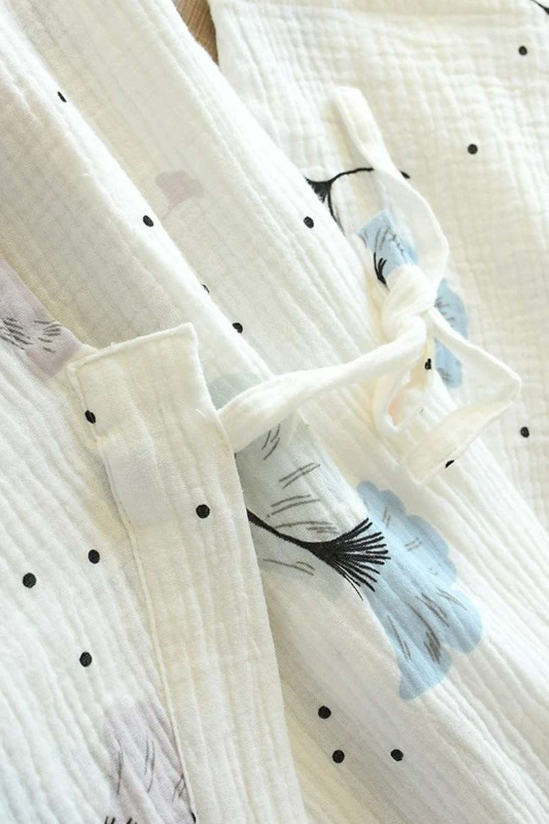 Kimono en gaze de coton blanc avec motifs floraux bleus et noirs, présentant une texture douce et légère